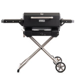 Parrilla asador portátil Masterbuilt a carbón sobre su carrito plegable de patas cruzadas y ruedas