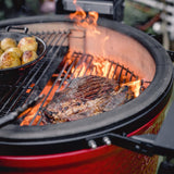 Churrasco y papas asándose sobre la parrilla del Kamado Joe con las llamas al fondo