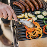Chorizos, calabacín y pimentones asándose en la parrilla portátil