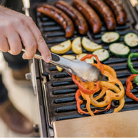 Chorizos, calabacín y pimentones asándose en la parrilla portátil