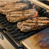 Churrascos sellándose sobre las brasas de la parrilla portátil a carbón
