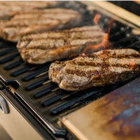 Churrascos sellándose sobre las brasas de la parrilla portátil a carbón