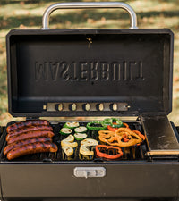 Tapa abierta de la parrilla portátil con chorizos y verduras sobre las rejillas