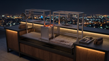 Parrilla doble con brasero central en cocina exterior de terraza de noche