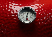 Termómetro de asador sobre superficie roja, ideal para controlar temperatura en parrillas y ahumadores