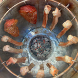 Carne y costillas asándose en barril asador jumbo de acero inoxidable con carbón encendido